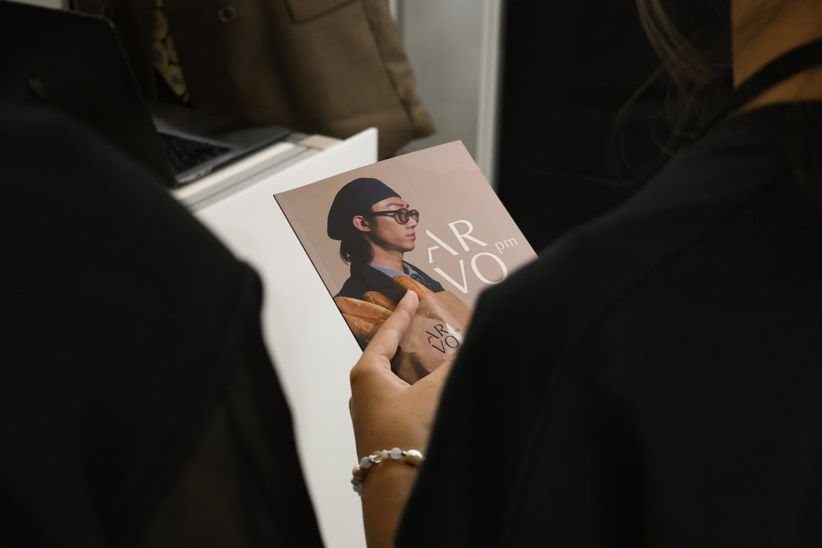 A visitor looking through the ARVOpm catalogue at the SS26 trade event in 2025.